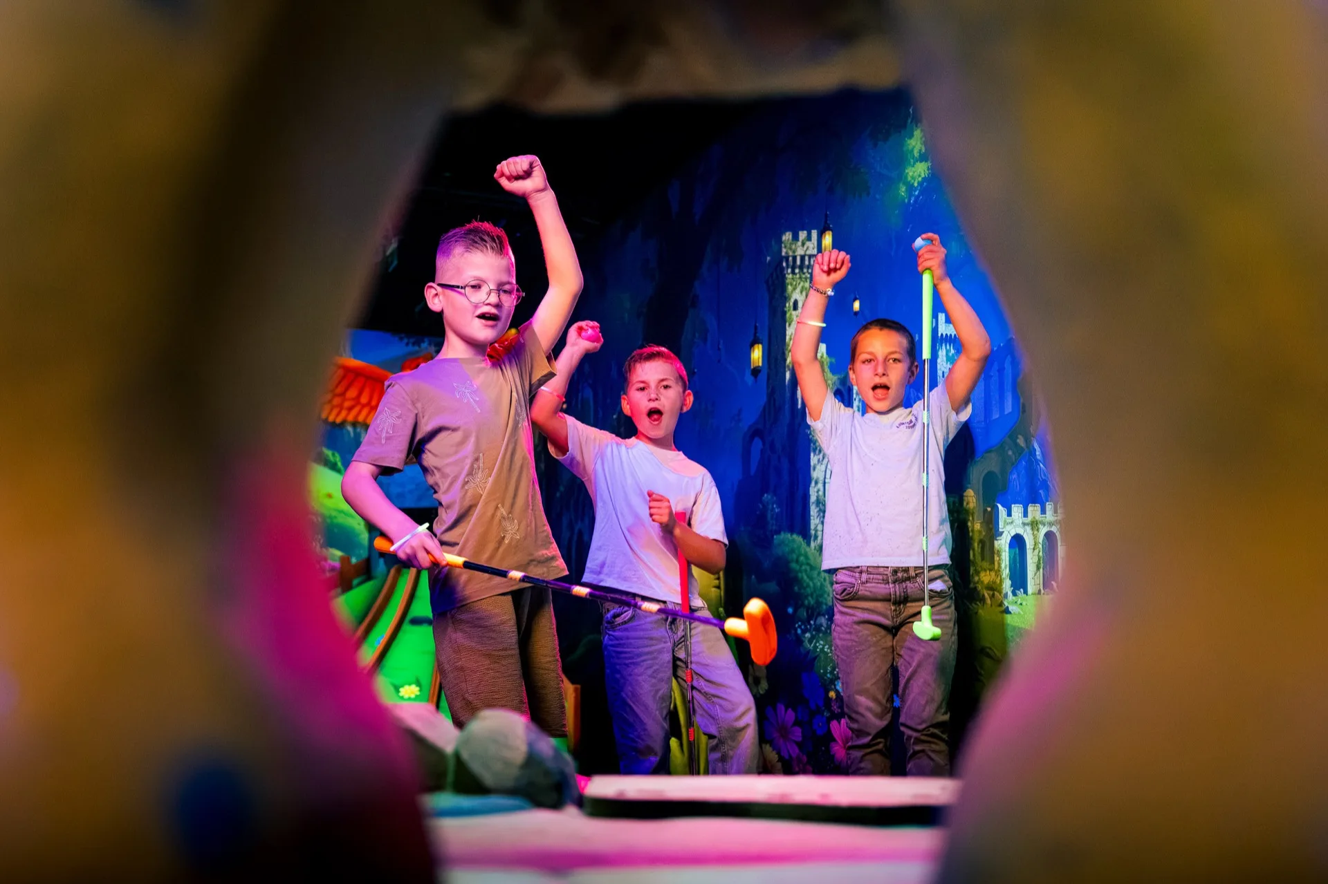 Jongens vieren feest met hun glowgolfclub omhoog tijdens een kinderfeestje bij Pixel Play Kerkrade